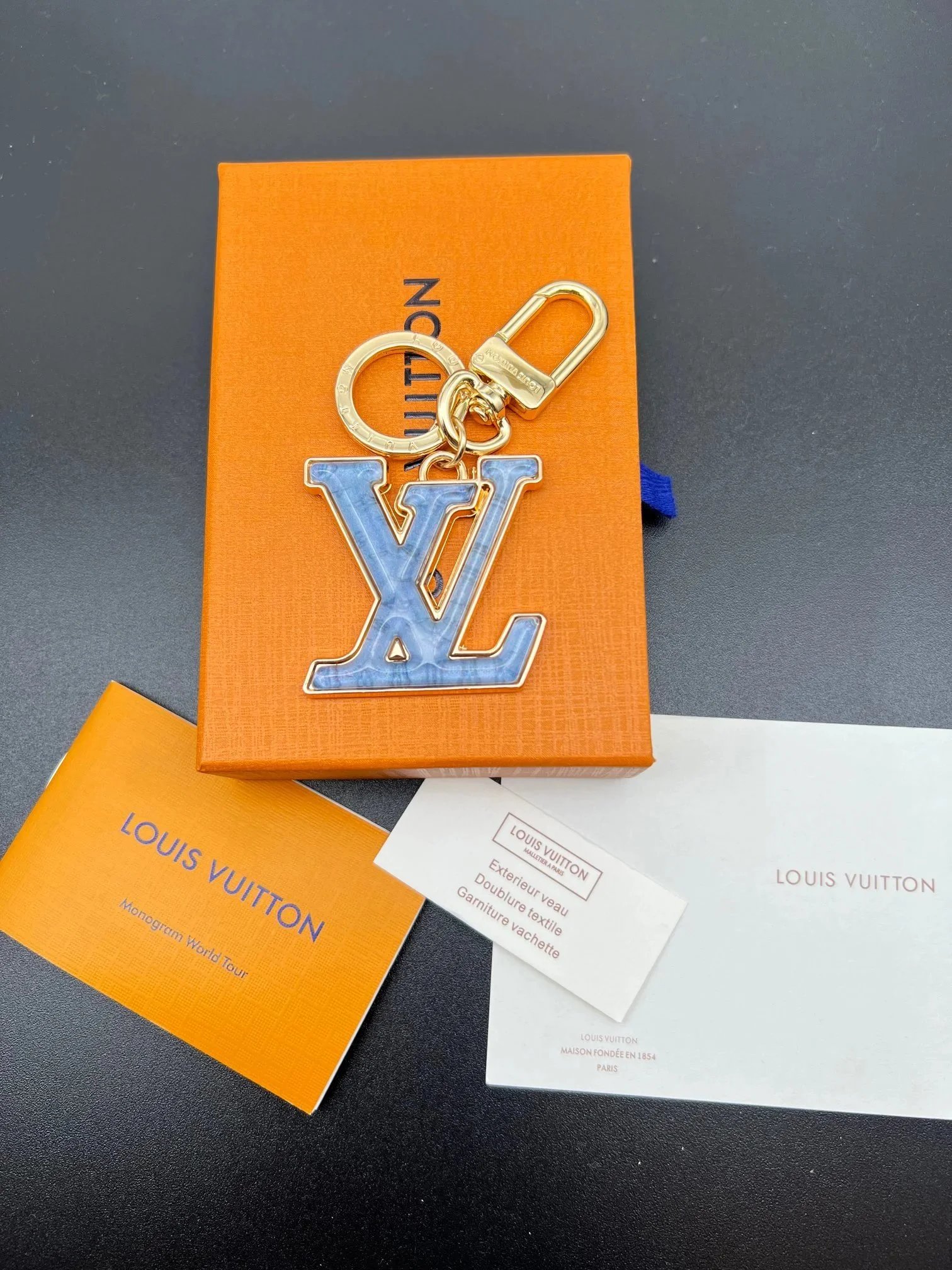 Llavero Louis Vuitton con iniciales LV y colgante azul jaspeado