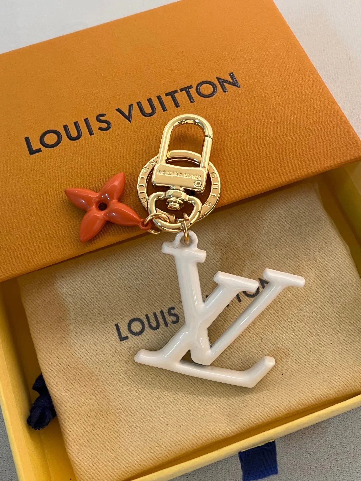 Llavero Louis Vuitton con colgantes de letra y flor en blanco y naranja