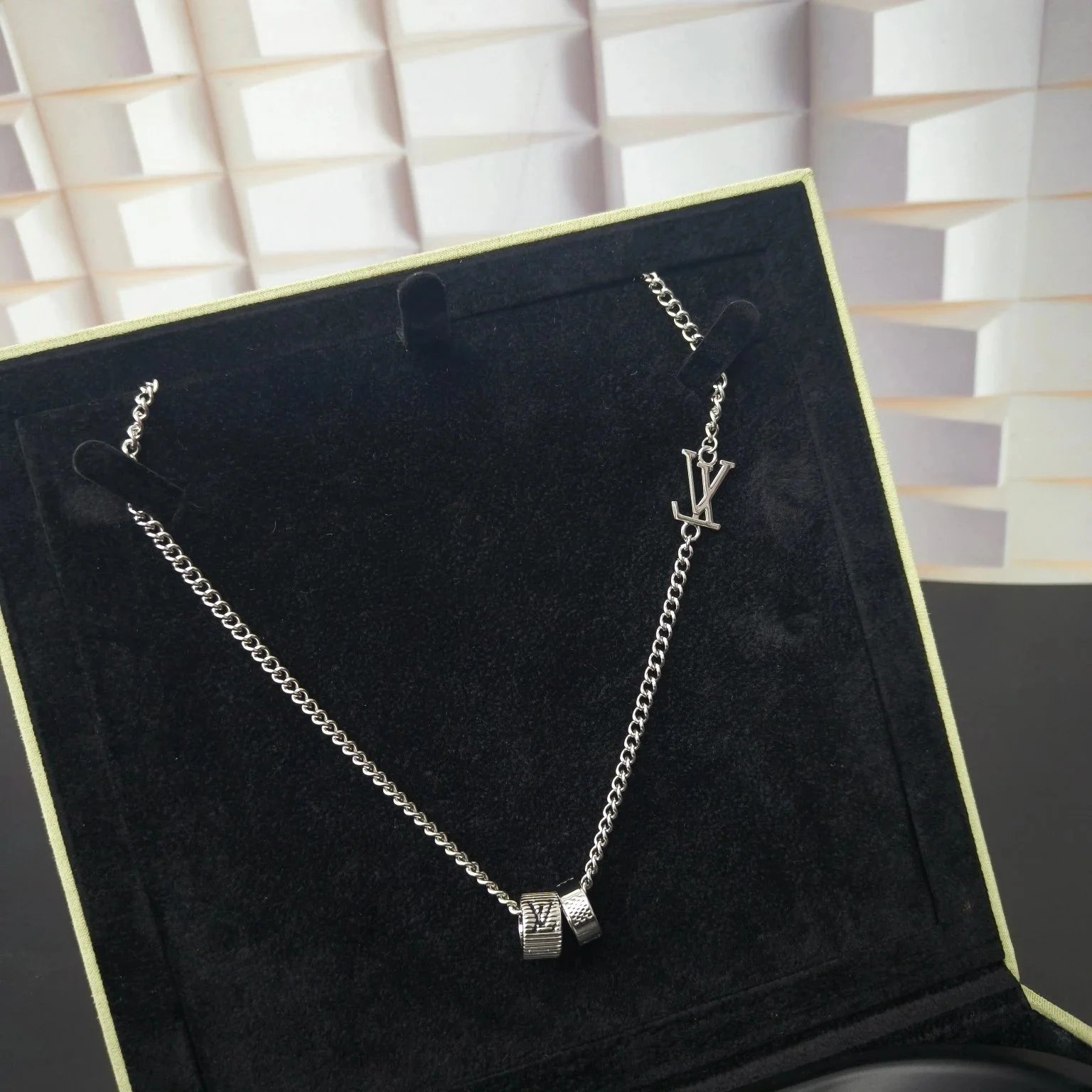Ketting met zilverkleurige schakel, twee ringhangers en embleem met LV-initialen