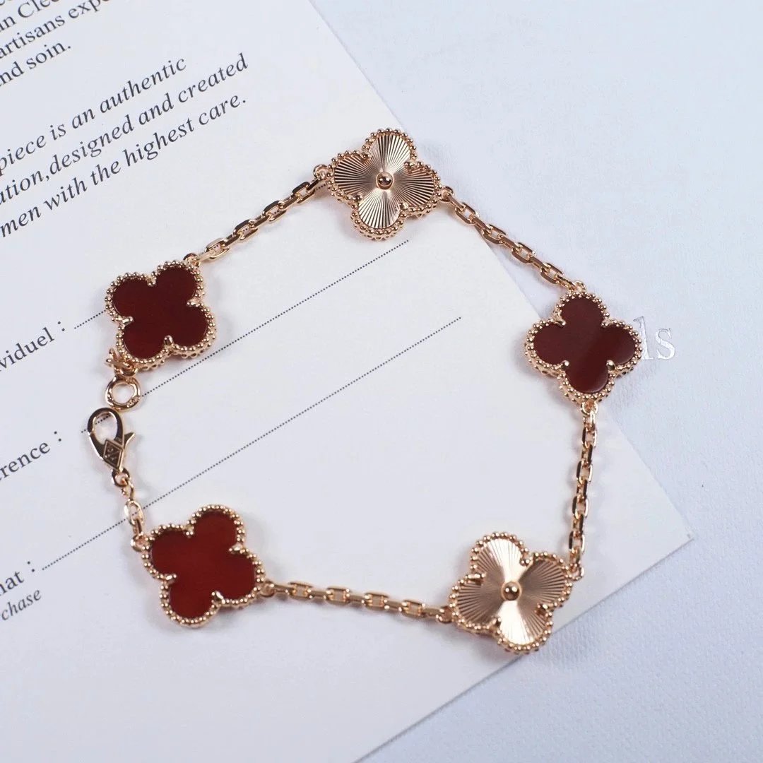 Pulsera de cadena con cinco tréboles de pétalos rojos y motivos metálicos en abanico