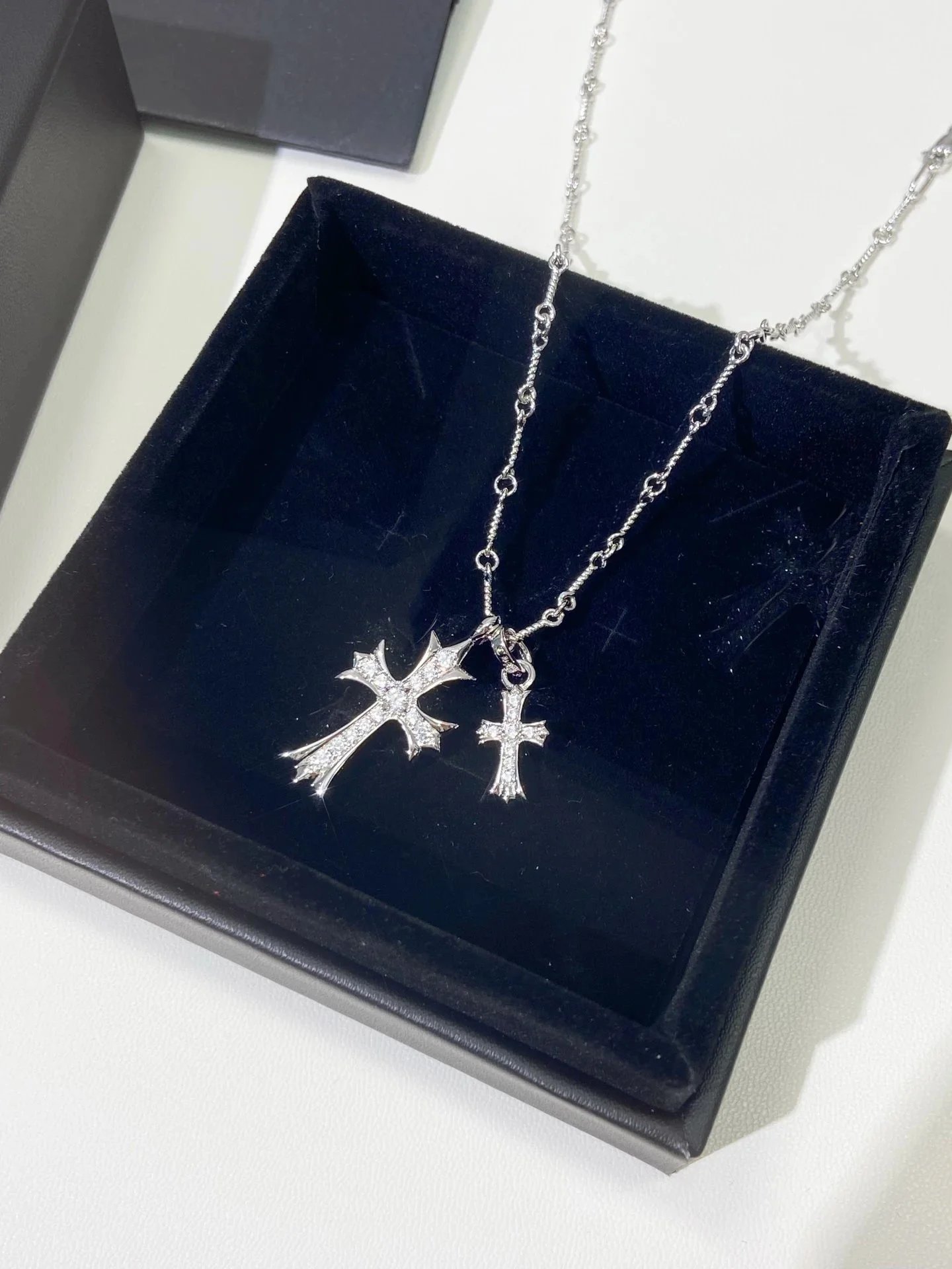 Collana con doppio ciondolo a croce color argento e incastonature testurizzate